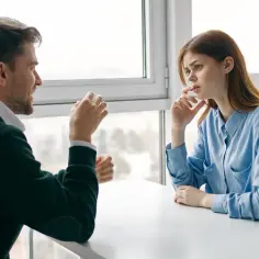 Mężczyzna tłumaczy kobiecie, jak przeprowadzić rozmowę oceniającą z trudnym pracownikiem. Kobieta słucha z uwagą, zamyślona.