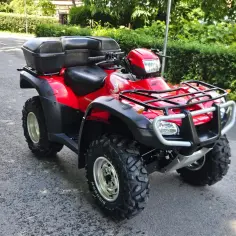 Czerwony quad Honda TRX 700 z dwoma czarnymi kuframi, gotowy na przygodę w terenie.