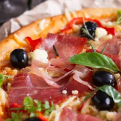 Pyszna pizza z cienko pokrojoną, aromatyczną szynką, czarnymi oliwkami i papryką. Idealna na każdą okazję, zastanawiasz się jaka szynka na pizzę będzie najlepsza? Ta wygląda wyśmienicie!