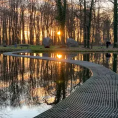 Zachód słońca nad stawem w Orońsku. Kręta kładka i odbijające się w wodzie drzewa tworzą magiczny widok. Oto jedne z wielu orońsko atrakcji.