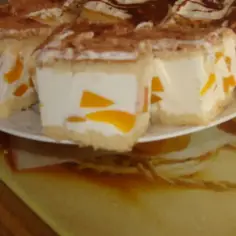 Sernik z bitą śmietaną Siostry Anastazji, z kawałkami brzoskwiń, posypany kakao. Pyszny deser na talerzyku.