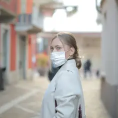 Kobieta w masce na twarzy, zastanawia się, ile można być na L4, idąc ulicą.