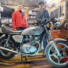 Dwóch mężczyzn w garażu obok klasycznego motocykla Suzuki GS400.