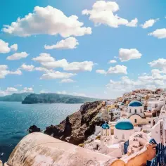 Santorini z błękitnymi kopułami kościołów i białymi domkami na klifie. Marzysz o podróży? Sprawdź, ile trwa lot z Grecji do Polski.