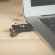 Pendrive podłączony do laptopa, gotowy do zgrania muzyki z telefonu.