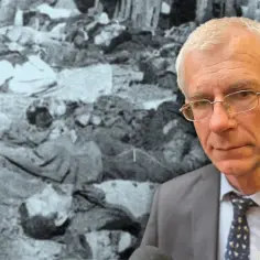 Mężczyzna w garniturze na tle sceny przedstawiającej ofiary zbrodni wołyńskiej.