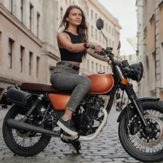 Kobieta na motocyklu 125cc, gotowa na jazdę po mieście. Stylowa, pewna siebie, z wolnością w oczach.
