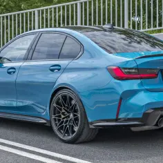 Niebieskie BMW M3 z dyfuzorem i czterema końcówkami wydechu, zaparkowane na drodze.