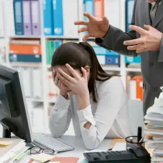Zastanawiasz się, jak sprawdzić toksyczną atmosferę w firmie jeszcze przed podpisaniem umowy? Obraz pokazuje zestresowaną pracownicę i agresywnego przełożonego.