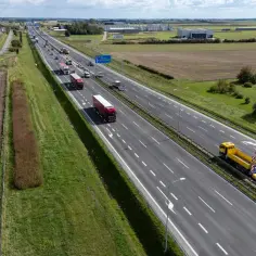 Autostrada A2: aktualności dzisiaj. Ciężarówki i żółty transporter na pustej drodze, w tle pola i budynki.