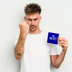 Zirytowany mężczyzna pokazuje kartkę z napisem "WiFi", jakby chciał powiedzieć: "Mam dość! Czas dowiedzieć się, jak zmienić hasło do wifi!".