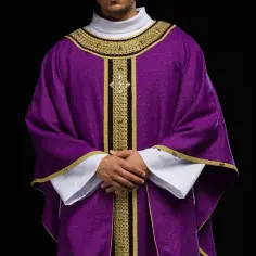 Kapłan w fioletowej szacie liturgicznej, symbolizującej kolor adwentu, z bogatymi złotymi zdobieniami.