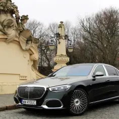 Elegancki Maybach S680 na tle zabytkowej architektury i drzew.