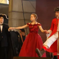 Tancerze w strojach z epoki, w tym wampir w czerwonym płaszczu, biorą udział w musicalu "Taniec wampirów".