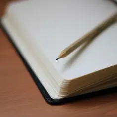 Otwarty notatnik z ołówkiem na drewnianym blacie. Czy notatka służbowa musi być podpisana przez pracownika?