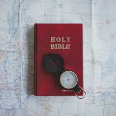 Czerwona Biblia i kompas na mapie. Pismo Święte wskazuje drogę, jak nie cudzołożyć, co to znaczy żyć w zgodzie z Bogiem.