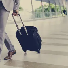 Biznesmen z walizką w drodze na lotnisko. Dowiedz się, jak rozliczyć bilety MPK i taksówki w delegacji zagranicznej.