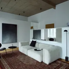 Nowoczesny salon z białym narożnikiem, czarnym fotelem i obrazem gwiazd.
