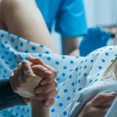 Wsparcie w trakcie porodu. Dłoń partnera trzyma dłoń rodzącej, gdy zbliża się odejście czopu śluzowego a rozwarcie.
