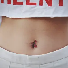 Kolczyk w pępku, jak zrobić go bezpiecznie? Zobacz zbliżenie na brzuch z błyszczącym piercingiem.