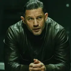 Tom Hardy w skórzanej kurtce, członek obsady "Strefy gangsterów", spogląda w bok z zamyśloną miną.