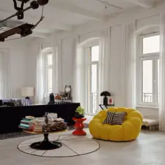 Jasne, oto opis:

Nowoczesny salon w stylu bauhaus z czarną sofą, żółtym fotelem i industrialnymi elementami.