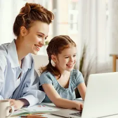 Mama i córka uczą się razem przy laptopie. Edukacja domowa wady i zalety – wspólna nauka to zaleta!
