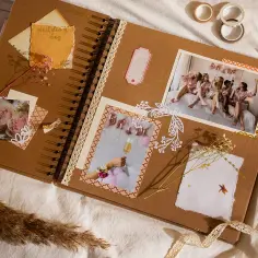 Otwarta księga wspomnień, gdzie co to jest scrapbooking widać na zdjęciach z wesela, ozdobiona taśmami i suszonymi kwiatami.
