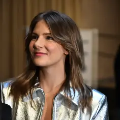 Marta Wierzbicka w srebrnej kurtce, uśmiecha się do rozmówcy.