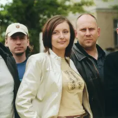 Grupa ludzi, w tym wokalistka Varius Manx, pozuje do zdjęcia na tle zieleni.