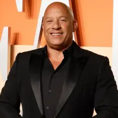 Vin Diesel, gwiazda "Szybcy i wściekli 11", uśmiecha się szeroko w czarnym smokingu.