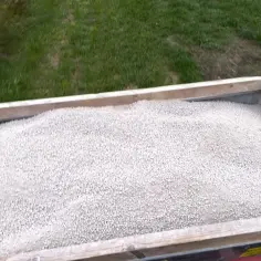 Zbiornik nawozu z wapnem palonym, gotowy do rozsiewu na zielonej trawie.