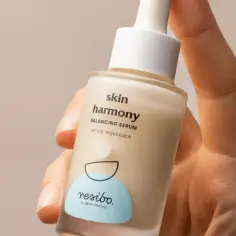 Dłoń trzyma buteleczkę serum Resibo. Składnik alantoina dba o harmonię skóry.