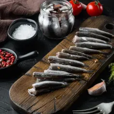 Świeże ryby, przygotowane do marynowania, to właśnie co to jest anchois. Obok sól, pieprz i czosnek.