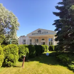 Elegancka restauracja "Marmas Jastrzębia Góra" otoczona zielenią, z wypielęgnowanym ogrodem i drzewami.