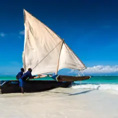 Dwaj mężczyźni przygotowują tradycyjną łódź do rejsu. Marzysz o podróży? Sprawdź, ile się leci na Zanzibar z Poznania!