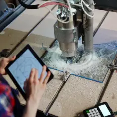 Operator kontroluje pracę frezarki CNC na tablecie, która precyzyjnie wycina wzór. To pokazuje, cnc co to za technologia.