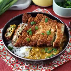Chrupiące katsu na ryżu z sosem curry, posypane szczypiorkiem. Pyszne danie, które z pewnością zaspokoi głód.