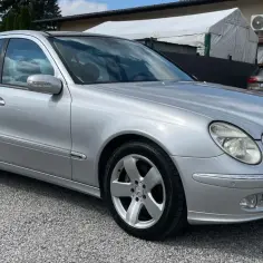 Srebrny Mercedes E500 W211 na żwirowym podjeździe, gotowy na podróż.