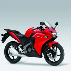 Czerwony motocykl sportowy Honda CBR 125R z czarnym siedzeniem i felgami, gotowy do jazdy.