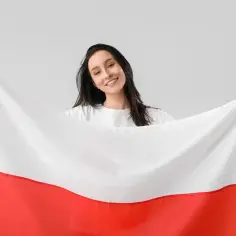Uśmiechnięta kobieta trzyma polską flagę. Czy 3 maja jest dniem wolnym od pracy? Tak, to święto narodowe!