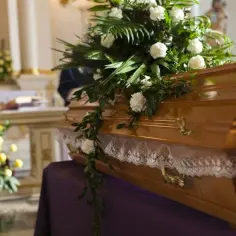 Drewniana trumna ozdobiona kwiatami w kościele. Zastanawiasz się, ile w Polsce kosztuje kremacja zwłok?
