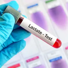 Rękawiczka w niebieskiej rękawiczce trzyma probówkę z krwią do testu na mleczan, kluczowego w diagnostyce kwasicy mleczanowej.
