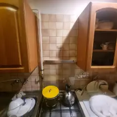 Zabudowa rury gazowej w kuchni, obok szafek i zlewu. Biały kot odpoczywa na blacie.