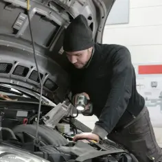 Mechanik z latarką bada silnik Renault, szukając przyczyny błędu DTC P0300.