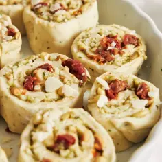Roladki z ciasta do pizzy z suszonymi pomidorami, orzeszkami pinii i parmezanem, gotowe do pieczenia.