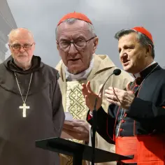 Trzech kardynałów w strojach liturgicznych, jeden w habicie, podczas ważnego zebrania.