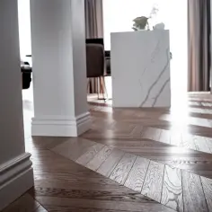 Eleganckie białe listwy przypodłogowe i parkiet w jodełkę tworzą stylowe wnętrze. Inspiracje dla Twojego domu.