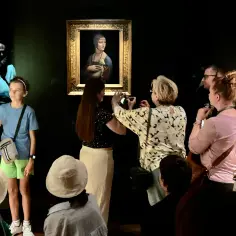 Grupa ludzi ogląda obraz "Dama z łasiczką" Leonarda da Vinci.