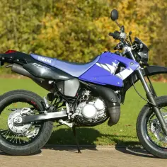 Niebieski motocykl Yamaha DT 125 na tle zieleni. Szczegółowe yamaha dt 125 dane techniczne dostępne dla miłośników terenowej jazdy.